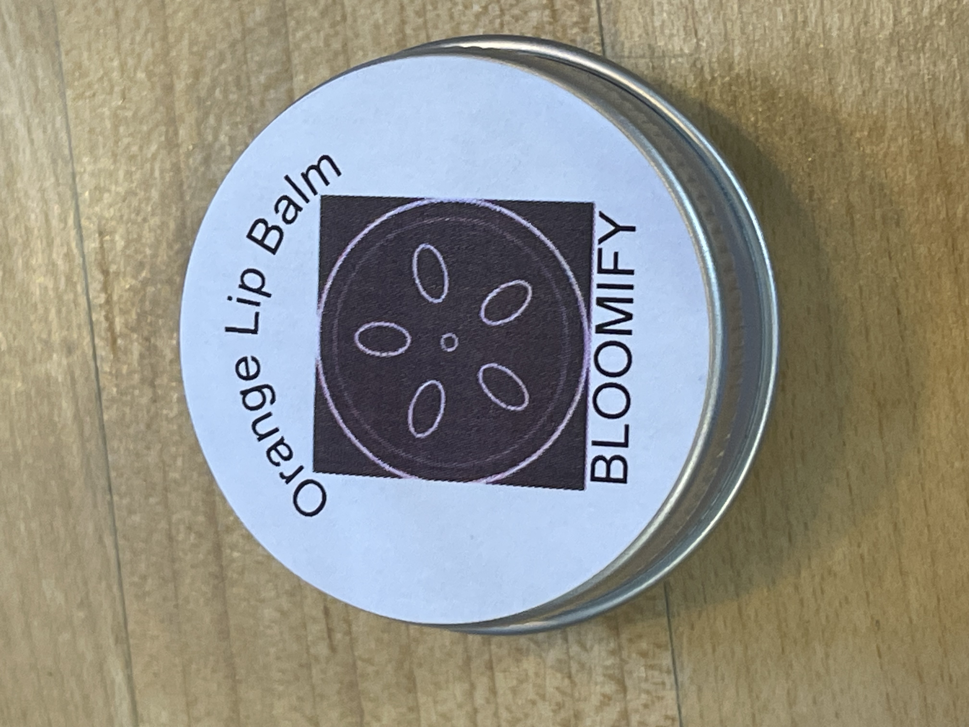 Orange Bloomify lip balm tin with label